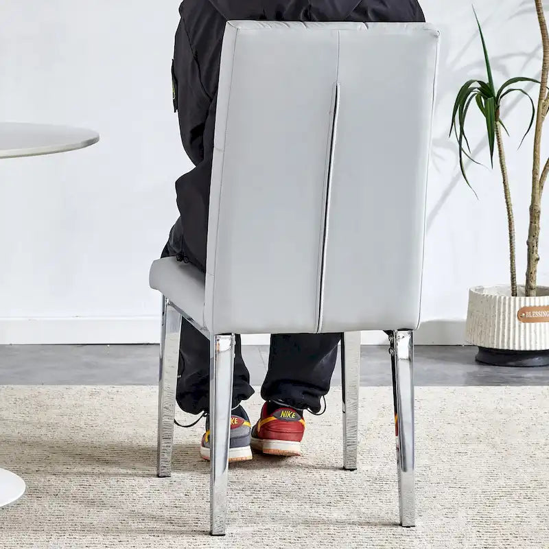 Chaise de salle à manger grise sans accoudoirs, avec dossier capitonné à motif quadrillé et clouté, et pieds en métal argenté.