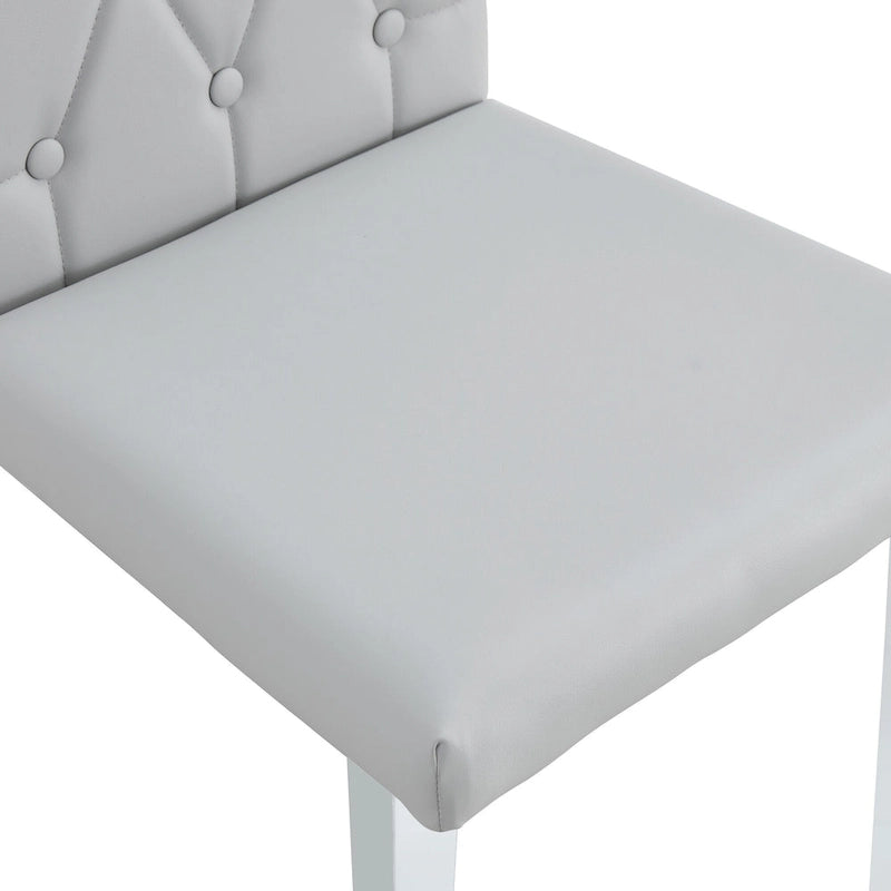 Chaise de salle à manger grise sans accoudoirs, avec dossier capitonné à motif quadrillé et clouté, et pieds en métal argenté.