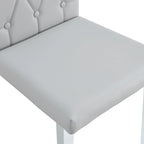 Chaise de salle à manger grise sans accoudoirs, avec dossier capitonné à motif quadrillé et clouté, et pieds en métal argenté.
