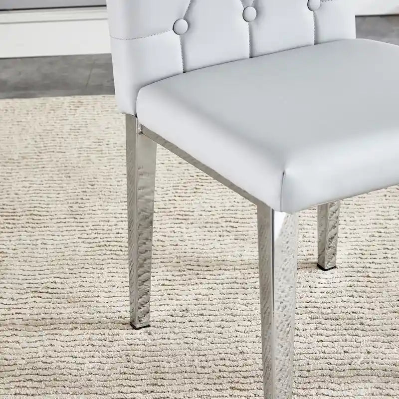 Chaise de salle à manger grise sans accoudoirs, avec dossier capitonné à motif quadrillé et clouté, et pieds en métal argenté.