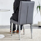 Chaise de salle à manger grise sans accoudoirs, avec dossier capitonné à motif quadrillé et clouté, et pieds en métal argenté.