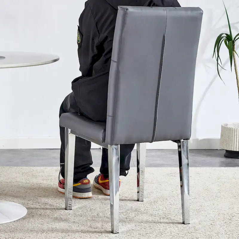 Chaise de salle à manger grise sans accoudoirs, avec dossier capitonné à motif quadrillé et clouté, et pieds en métal argenté.