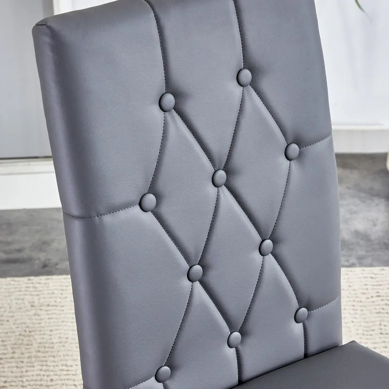 Chaise de salle à manger grise sans accoudoirs, avec dossier capitonné à motif quadrillé et clouté, et pieds en métal argenté.